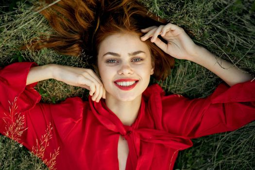 pretty woman in red dress lies on the grass landscape freedom. High quality photo