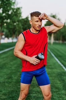Cheerful sporty man in the park on green grass doing exercises. High quality photo