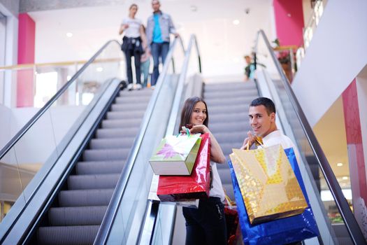 happy young couple with bags in shopping centre mall