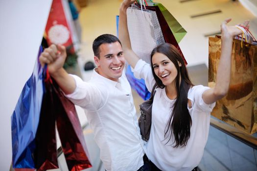 happy young couple with bags in shopping centre mall