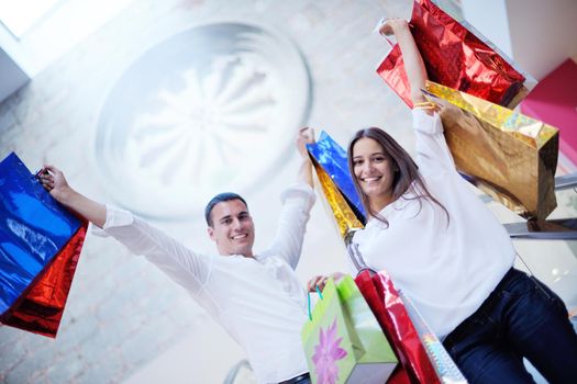 happy young couple with bags in shopping centre mall