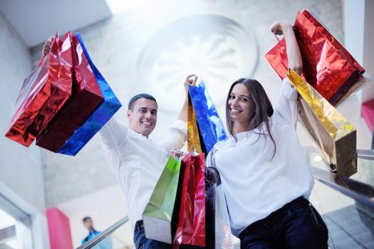 happy young couple with bags in shopping centre mall