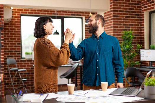 Businessman giving high five to manager woman after finising business project working at marketing presentation in startup office. Businesspeople analyzing management strategy planning company meeting