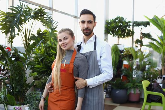 Portrait of pretty young consultants work in small flower delivery shop and sale indoor plants in pots. Business, floral design, creative studio concept