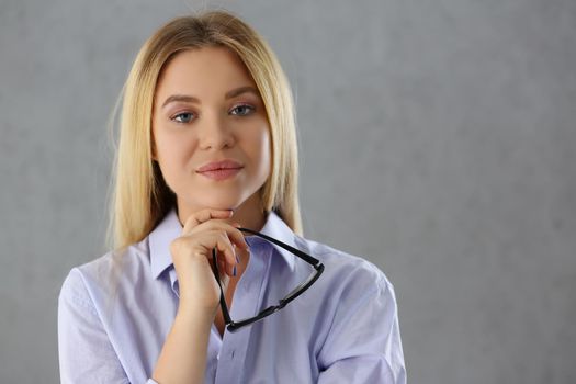 Portrait of attractive young woman posing in strict outfit hold black glasses. Blonde successful female confident model. Modeling, psychologist concept