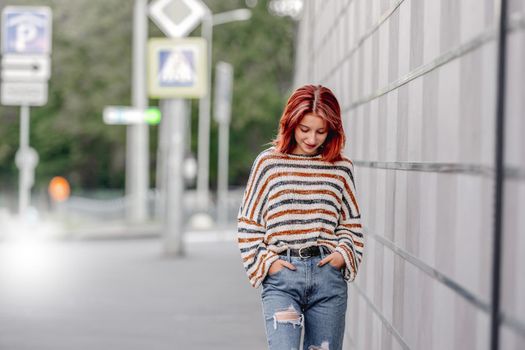 Stylish girl in casual trendy clothes walking at street. Urban portrait of pretty female teenager with bright hair