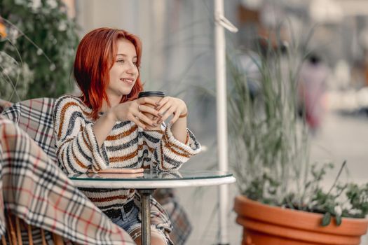 Pretty girl with coffee cup sitting in cafe in the morning. Stylish trendy teenager with hot drink at autumn