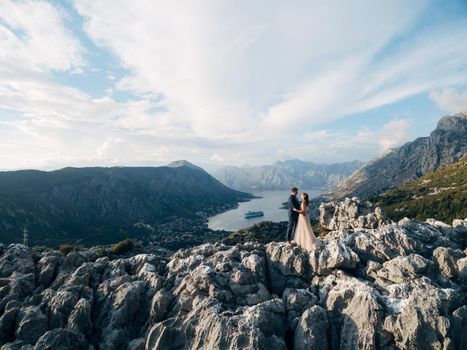 Groom and bride stand on the mountain overlooking the valley of the Kotor Bay. High quality photo