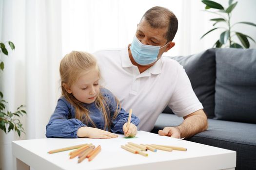 Grandfather and granddaughter drawing together in living room at home