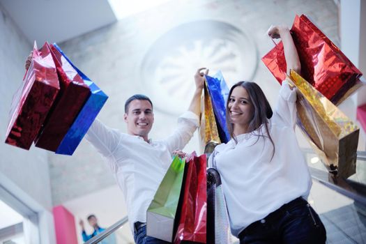 happy young couple with bags in shopping centre mall