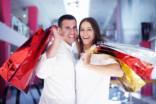 happy young couple with bags in shopping centre mall