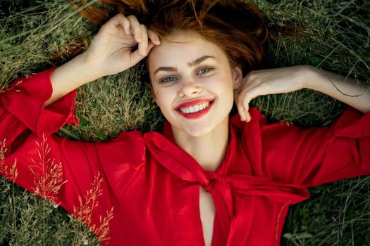 woman in red dress lies on the grass top view freedom. High quality photo