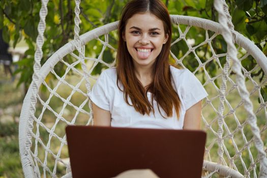 cheerful woman outdoors in hammock with laptop rest. High quality photo