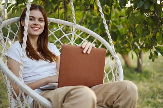 smiling woman outdoors in hammock with laptop technology. High quality photo