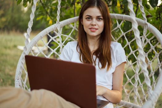 cheerful woman outdoors in hammock with laptop rest. High quality photo