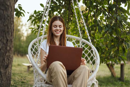 woman with laptop outdoors resting in hammock internet. High quality photo