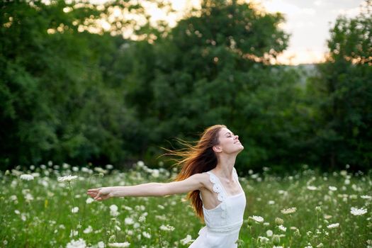 cheerful woman in a field with flowers in a white dress in nature. High quality photo