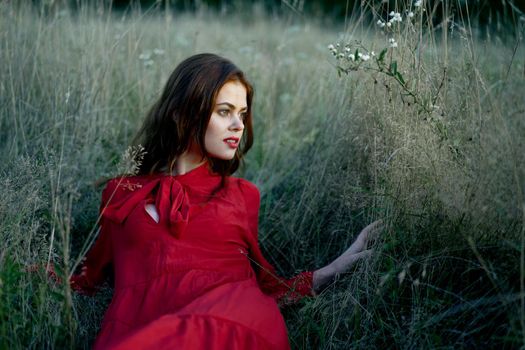 woman in red dress lies on the grass nature freedom rest. High quality photo