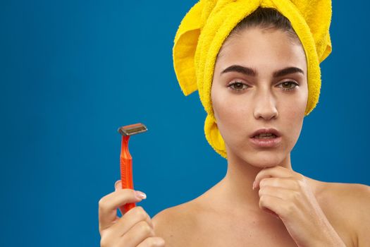 cheerful woman with a yellow towel on his head shaving blue background. High quality photo