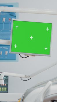 Dental team working with green screen on computer in cabinet for oral care. Dentist and assistant talking while looking at isolated background and mockup template for dentistry.