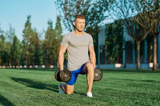 athletic man training with dumbbells in the morning Park. High quality photo