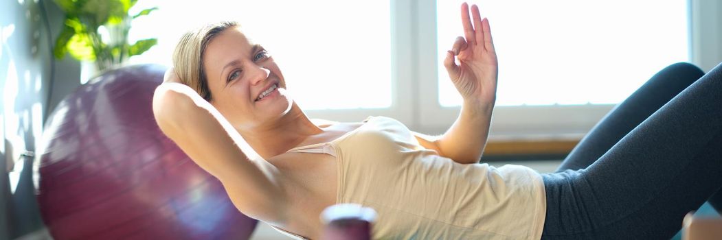 Smiling woman doing exercises on back roller. Recommended sports exercises for posture concept