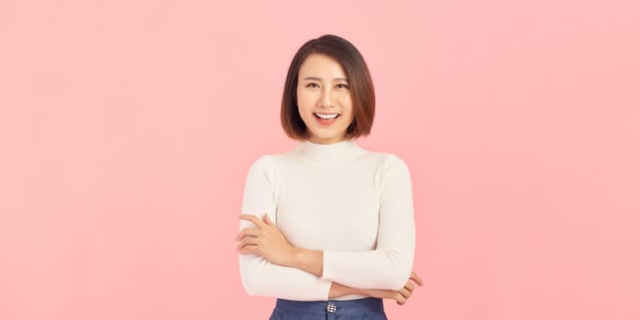 Confident business expert. Beautiful young woman in smart casual wear keeping arms crossed and smiling while standing against pink background