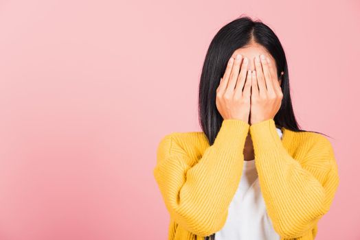 Asian portrait beautiful young woman in depressed bad mood her cry close face by hands because of being embarrassed studio shot isolated on pink background surprised and shocked with copy space