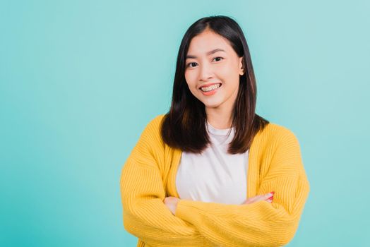 Young Asian beautiful woman smiling wear silicone orthodontic retainers on teeth with crossed arms, studio isolated on blue background, retaining tools after removable braces. Dental hygiene concept