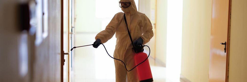 Virologist in protective hazmat suit disinfects surfaces in public and isolated areas. Pandemic health risk concept