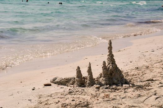 Sand figures on the shore of the beach. White sand, turquoise water, Mediterranean Sea.