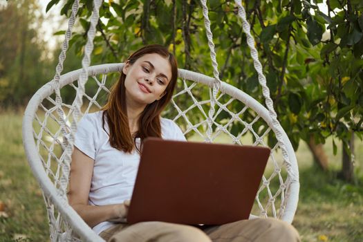 smiling woman outdoors in hammock with laptop technology. High quality photo