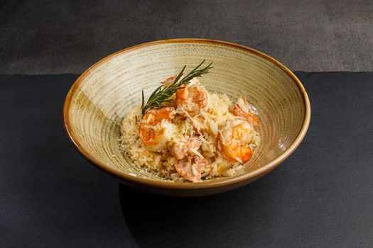 Risotto with fresh shrimps and herbs, dark background