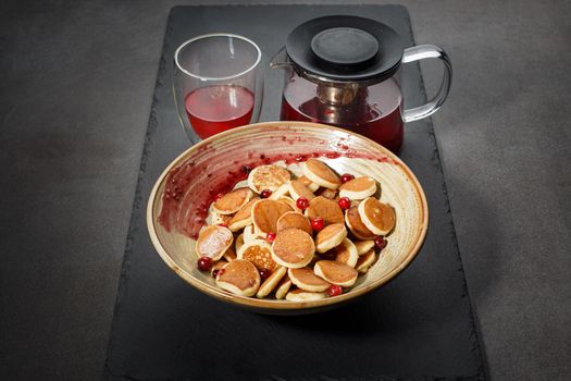 Dutch mini pancakes called poffertjes with red berries and tea. Healthy food concept.