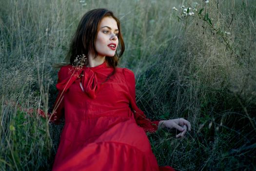 woman lies on the grass in a red dress landscape fashion. High quality photo