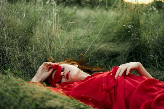 woman in red dress lying on the grass fresh air nature romance. High quality photo