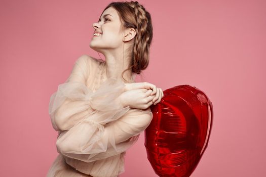 beautiful woman red heart in the hands of the balloon pink background. High quality photo