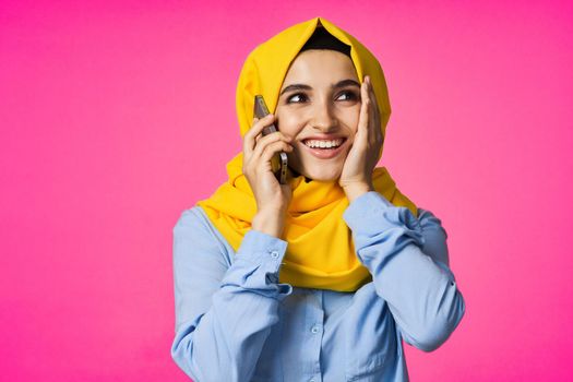 Muslim woman wearing hijab telephone communication technology pink background. High quality photo