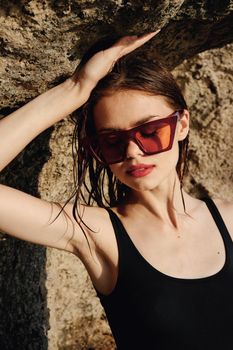 woman wearing sunglasses swimsuit dispensing rocks travel. High quality photo