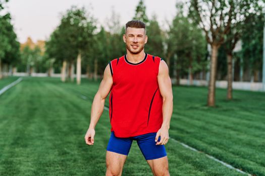 athletic man in red tank top posing outdoors fitness. High quality photo