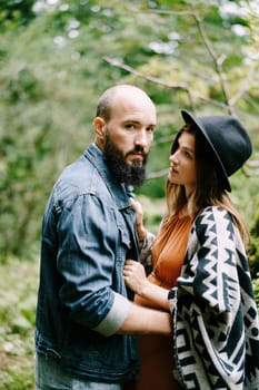 Bearded man hugs a pregnant woman in the park. Portrait. High quality photo