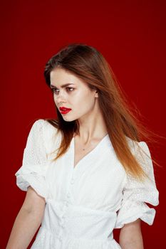 cheerful red-haired woman with red lips white dress red background. High quality photo