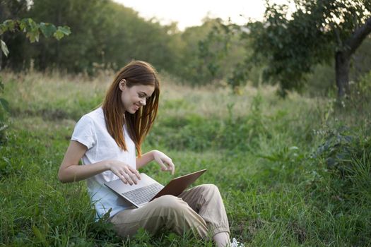 women outdoors in field with laptop leisure technology freedom. High quality photo