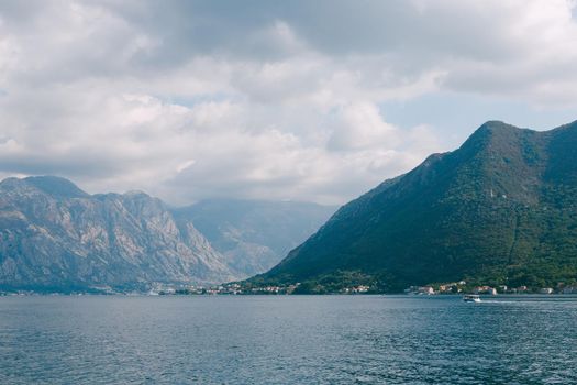 Boat sails along the Bay of Kotor against the backdrop of mountains. View from Perast. High quality photo