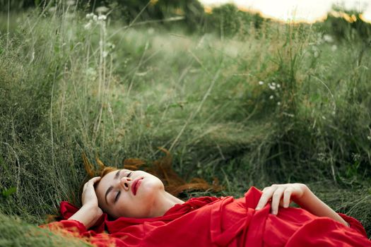 woman in red dress lying on the grass fresh air nature romance. High quality photo