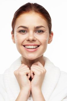 Woman in white robe posing fun skin care patches on face. High quality photo