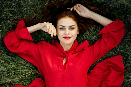 woman in a red dress lies on the grass fashion nature summer. High quality photo
