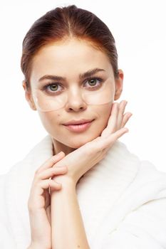 Woman in white robe posing fun skin care patches on face. High quality photo