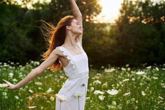 Woman in white dress in a field flowers sun nature freedom. High quality photo