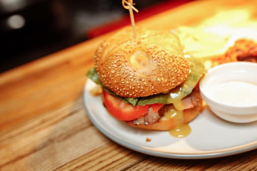 cheeseburgers and fries on table top with onion, tomato, lettuce and cheese.